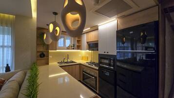 A modern kitchen with a central island, built-in oven, and a black refrigerator.