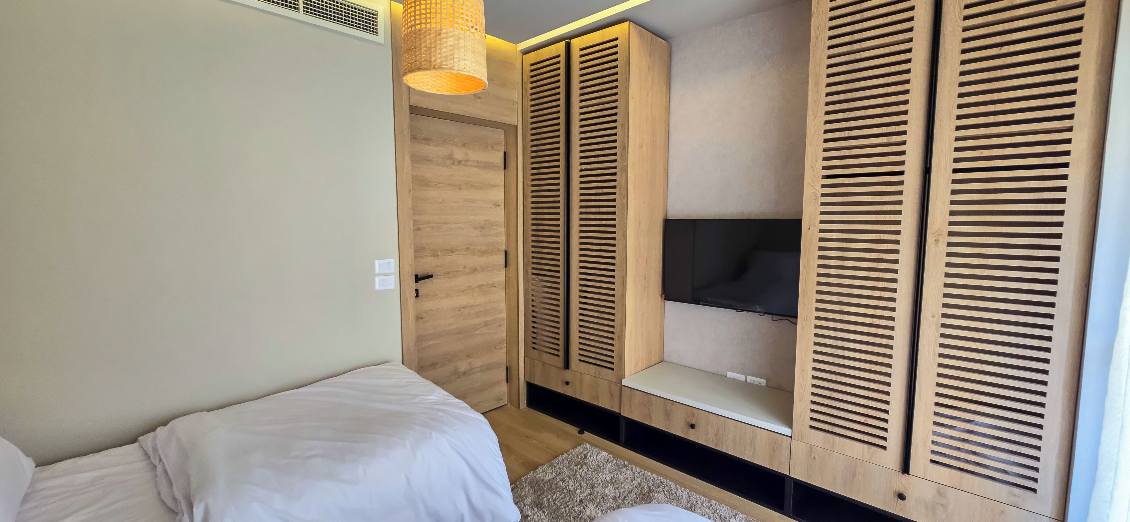 A bedroom with a bed, a wardrobe, and a television.