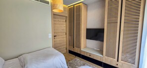 Une chambre à coucher avec un lit, une armoire et un téléviseur.