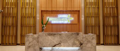 A reception desk with a marble top, flanked by wooden panel walls and a sign reading 'SunnyPlace Residences'.