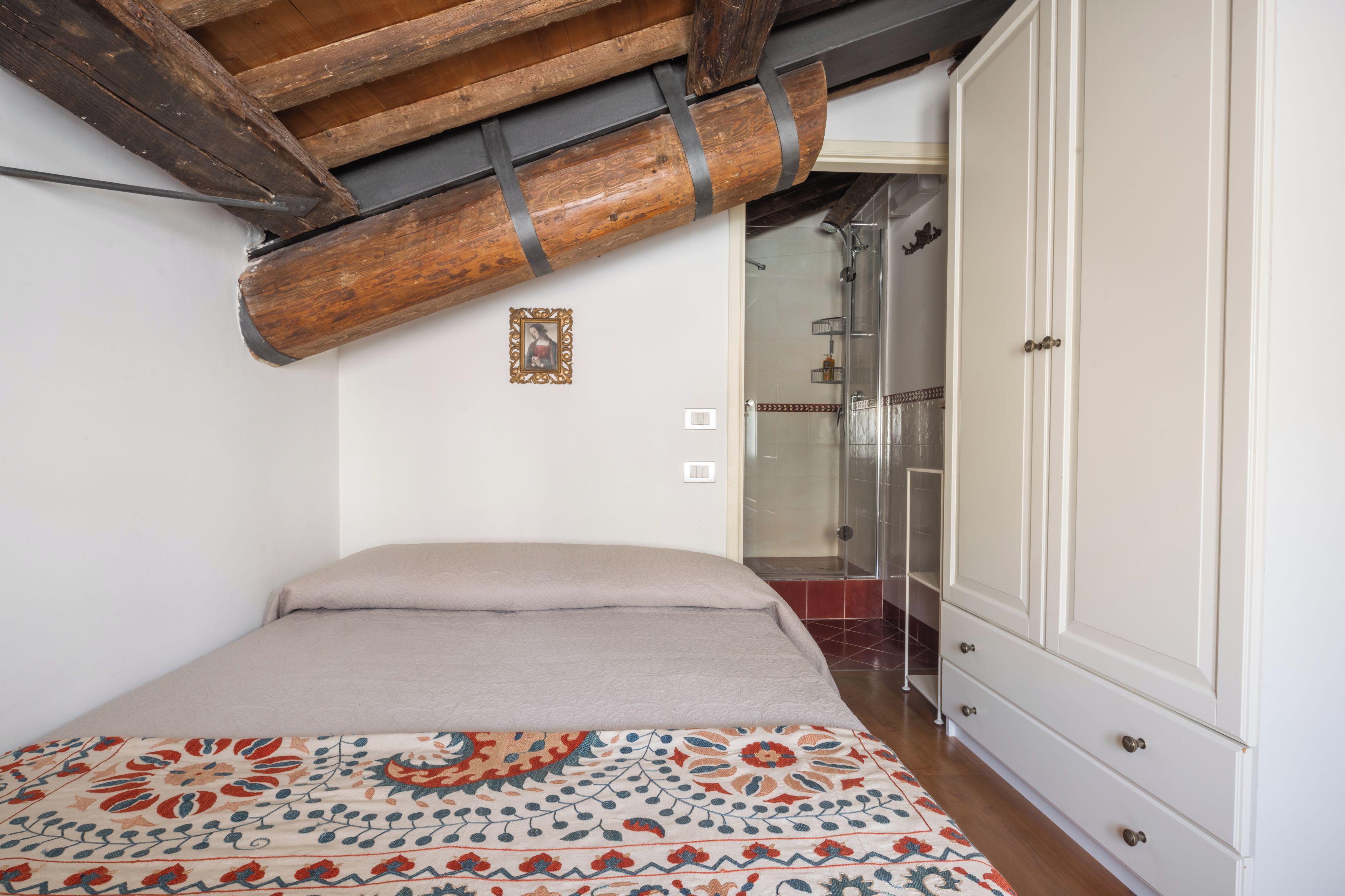 Ein Schlafzimmer mit einem Bett, einem Kleiderschrank und einer Duschkabine.