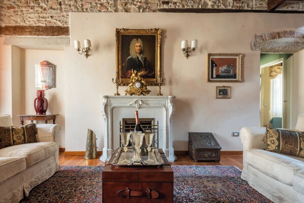 A traditional living room with a fireplace, a portrait above it, and a vintage trunk in the center.