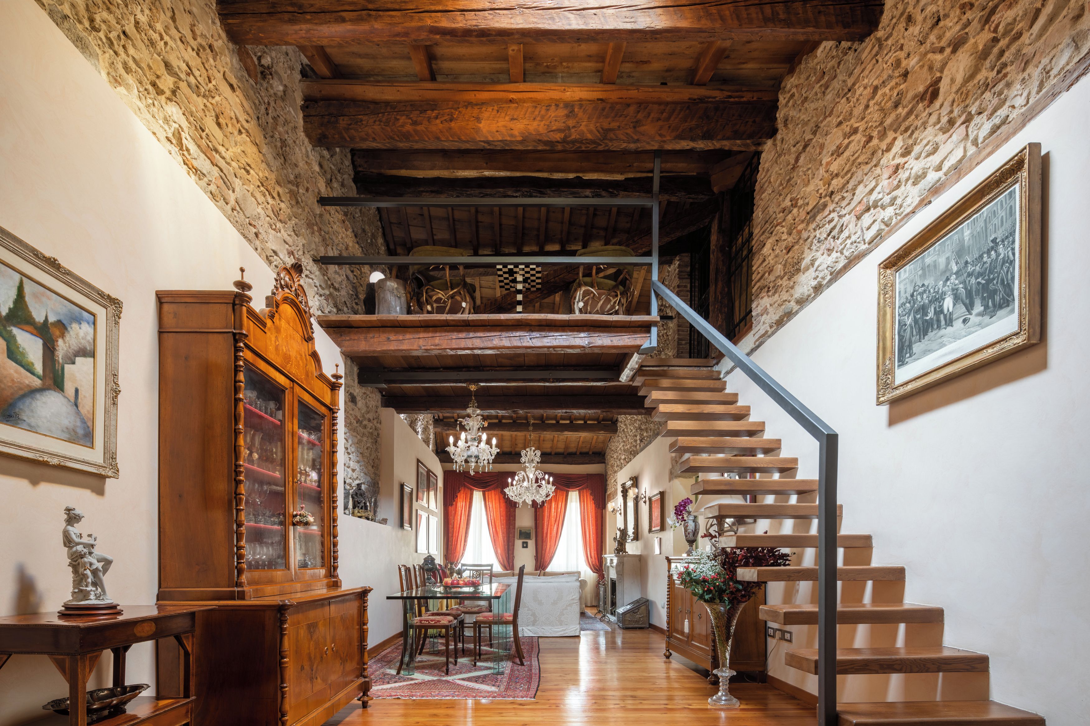 Un interior tradicional con una escalera de madera, un comedor y una araña.