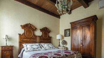Una camera da letto con un letto di legno, un comodino, una cassettiera, un lampadario e un quadro appeso al muro.