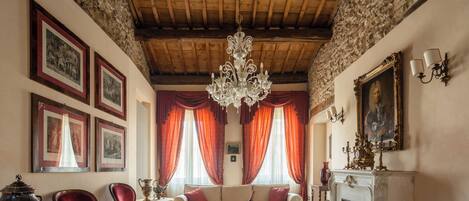Una habitación tradicional con techo de madera, un candelabro, chimenea y cuadros enmarcados en las paredes.