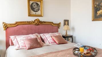 A bedroom with a large bed, a bedside table with a lamp, and a tray with breakfast items.