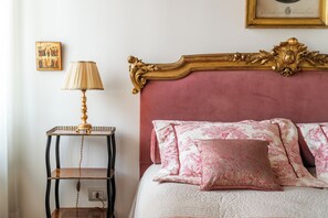 A bed with pink floral bedding and a gold ornate headboard.