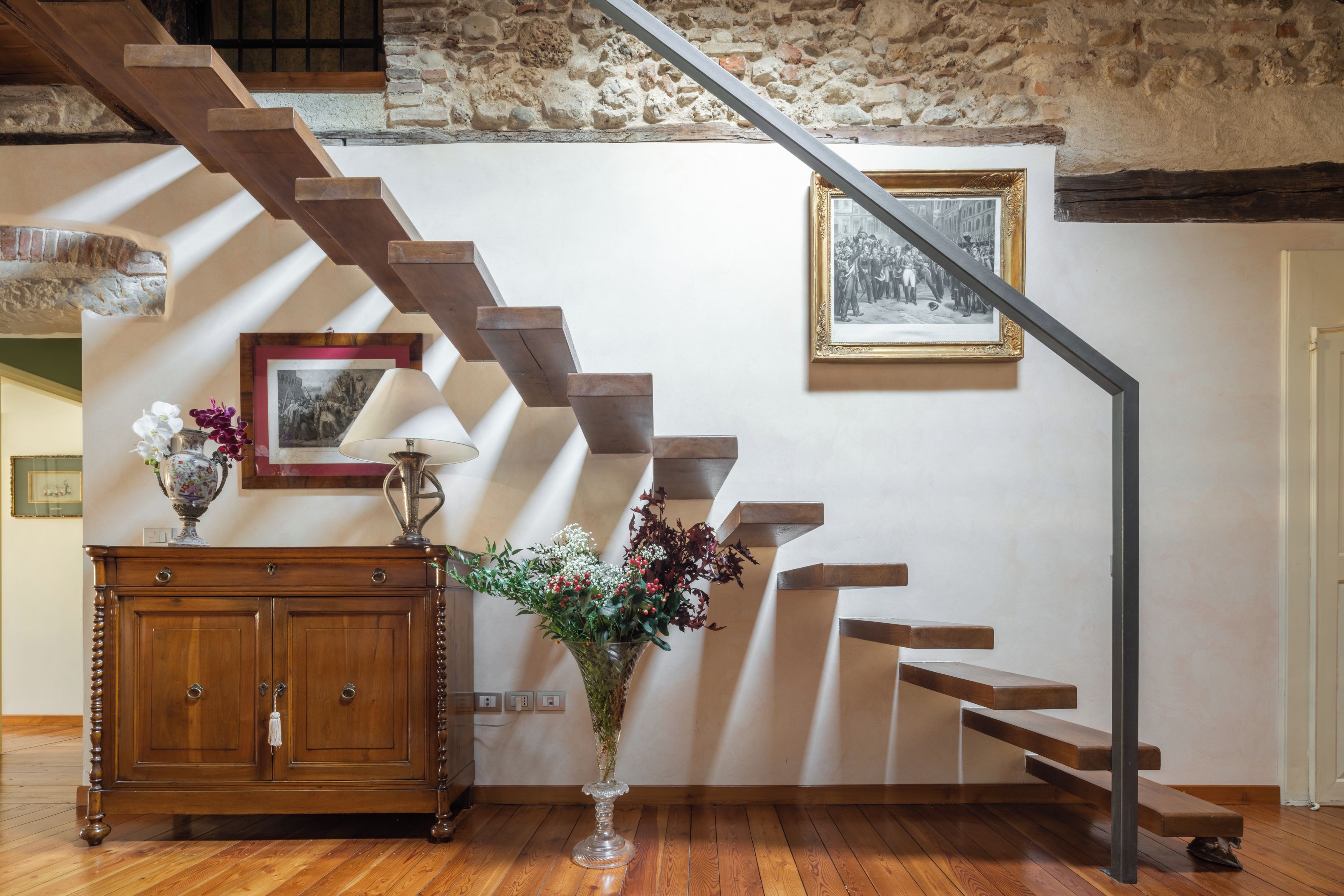 Una scala in legno con una parete in pietra e un quadro appeso al muro.