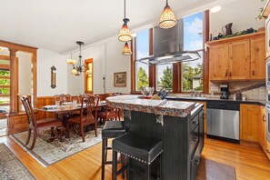 A modern kitchen with a central island, wooden cabinets, and pendant lighting. - The Sanctuary | Old Town Retreat & Garden Oasis (Fort Collins)