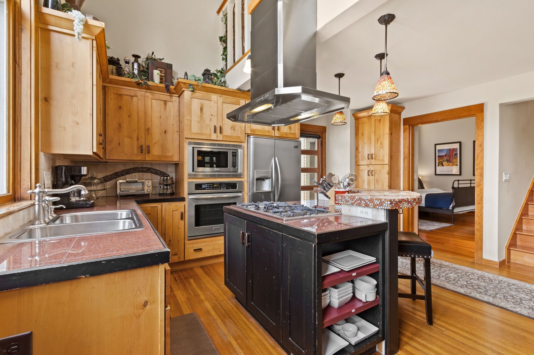 A modern kitchen with wooden cabinets, stainless steel appliances, and a central island with a sink.