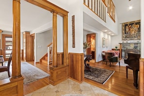 A spacious living area with a grand staircase, a piano, and a fireplace. - The Sanctuary | Old Town Retreat & Garden Oasis (Fort Collins)