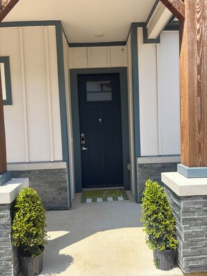 A front entrance with a dark blue door, a small window above it, and two potted plants on either side. - Spa-Inspired Escape Cozy 2BR/2BA with Private Yard in Fort Worth (Fort Worth)