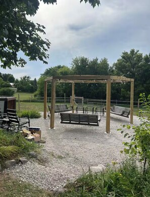An outdoor seating area with a pergola structure, benches, and a gravel ground.