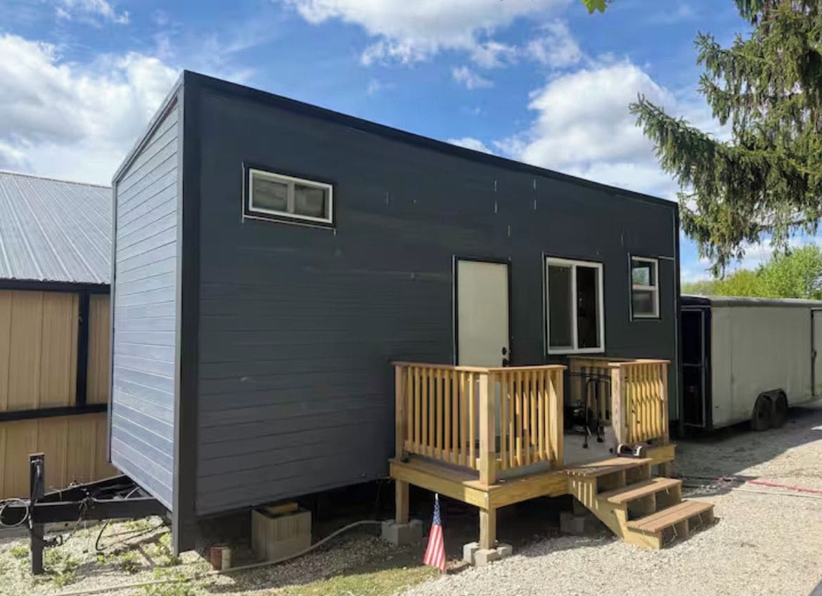 A mobile home with a wooden deck, a front door, and a small porch area.