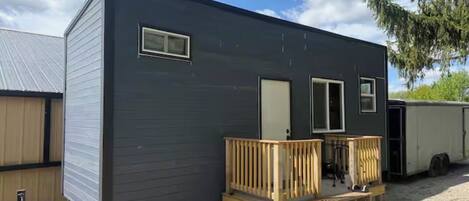 A mobile home with a wooden deck, a front door, and a small porch area.