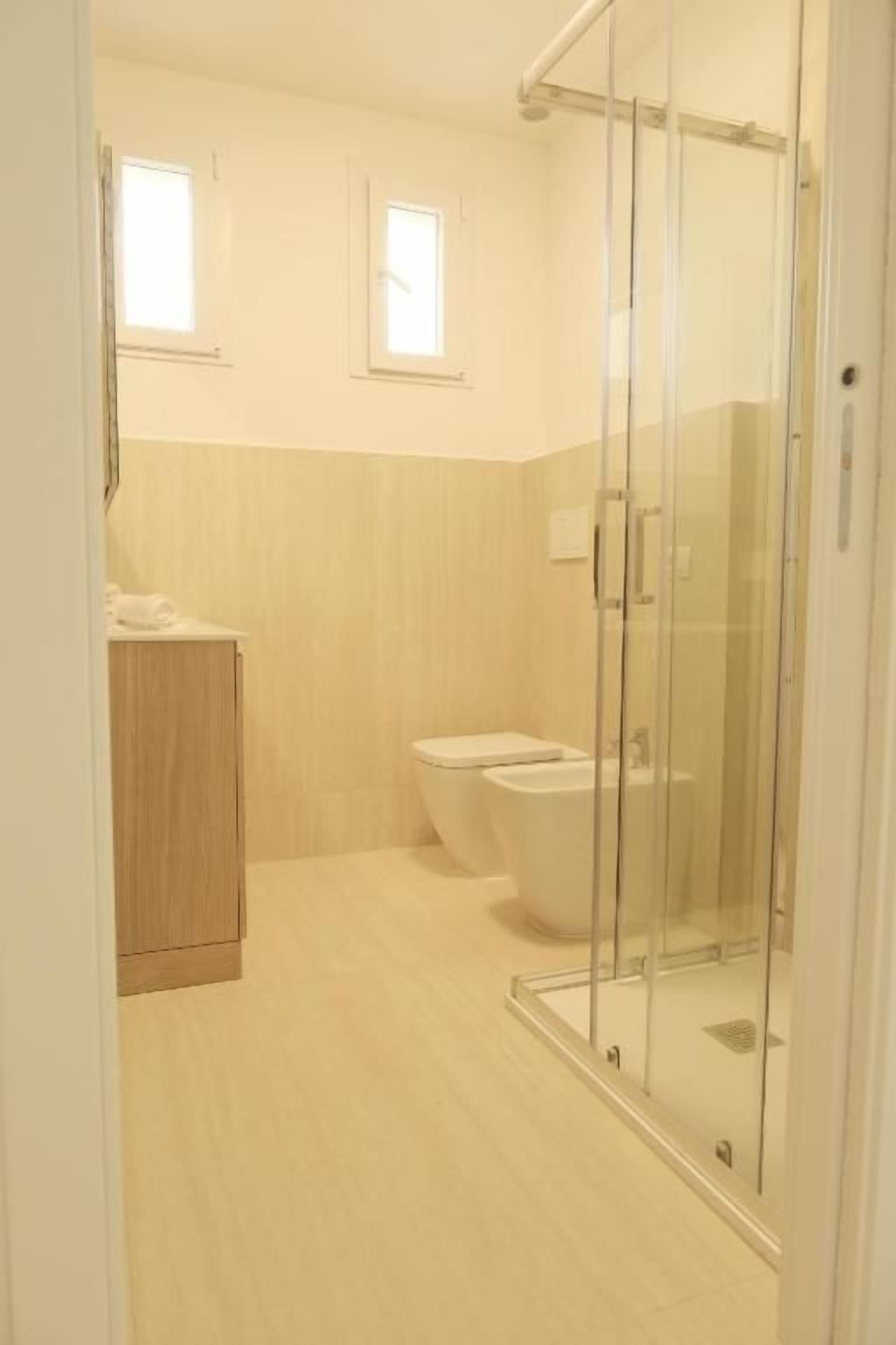 Un baño con ducha acristalada, inodoro y lavabo.