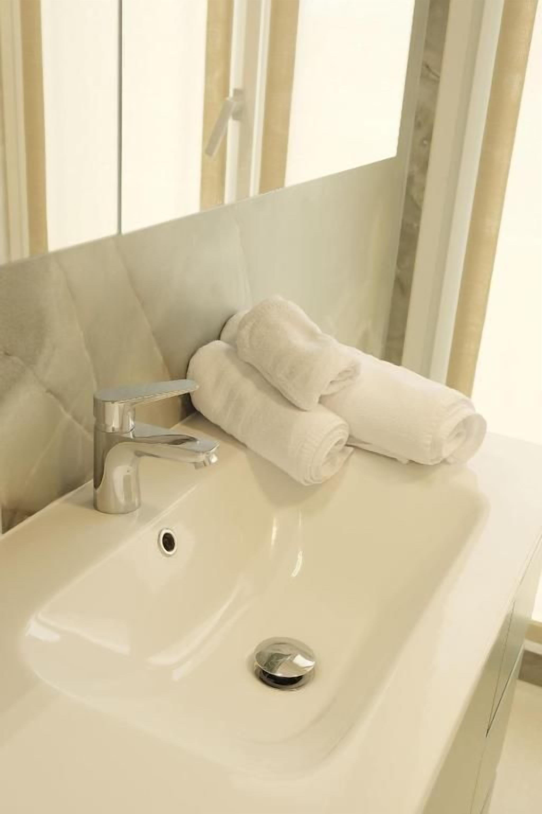 A bathroom with a sink, a towel rack, and a mirror.