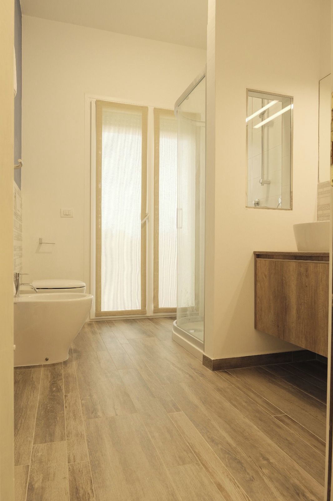 Une salle de bain comprenant des toilettes, un lavabo, un miroir et un espace douche.