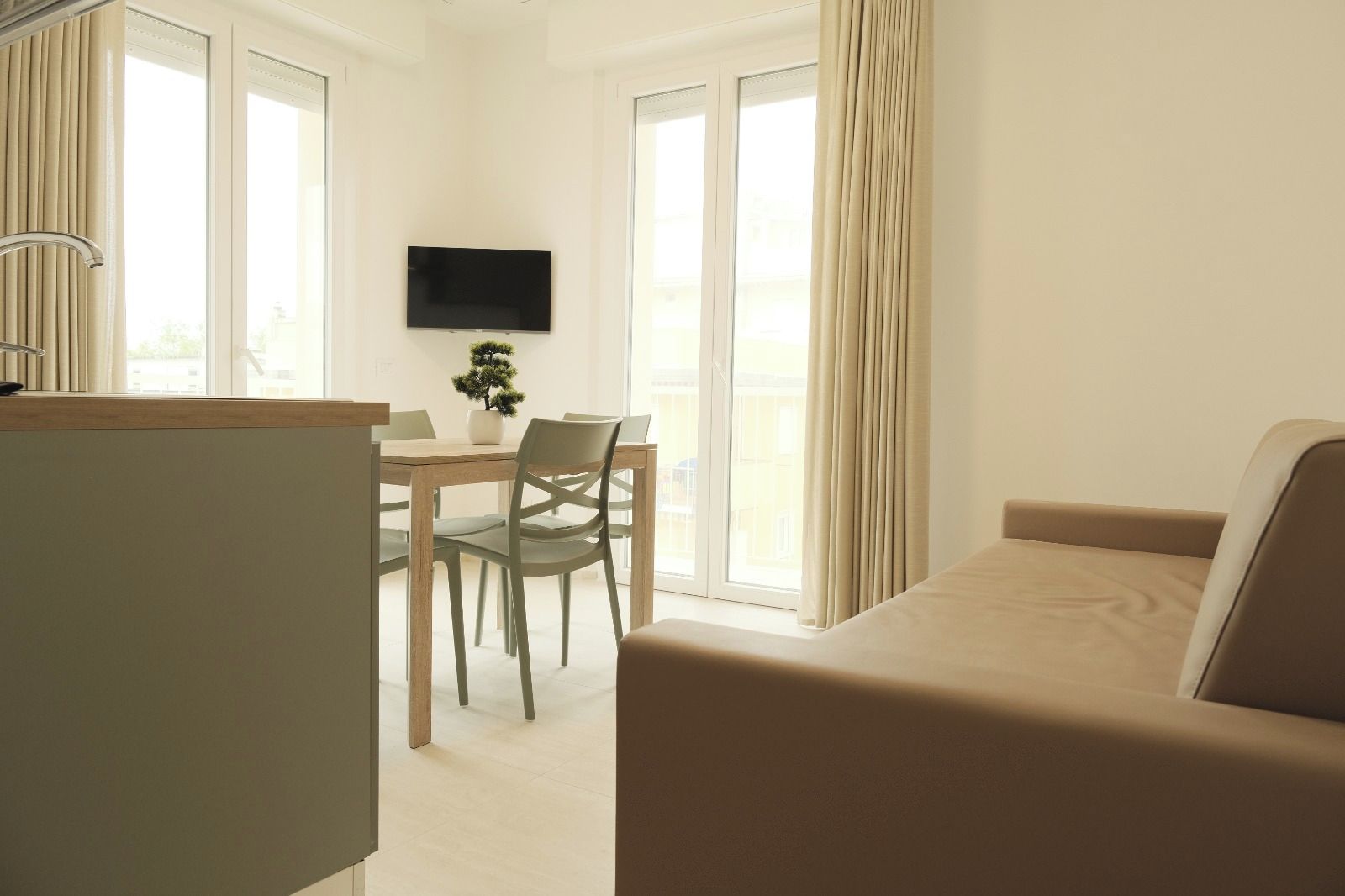 A hotel room with a bed, a desk with a chair, a television, and a window with curtains.