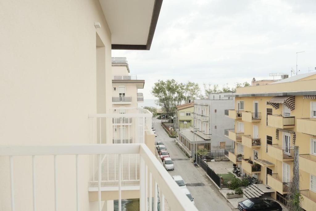 A residential building with balconies, a street view, and parked cars.
