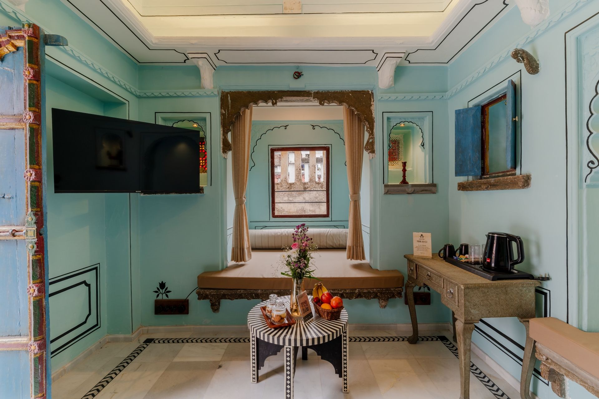 Una habitación de diseño tradicional, con una ventana con cortinas, una mesa con un florero y una zona de café.