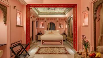 Een hotelkamer in roze tinten, met een bed, nachtkastje, een rode decoratieve boog en uitzicht op de gang.