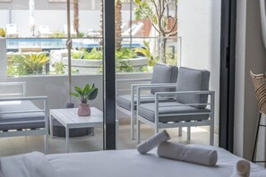 A hotel room with a balcony, a bed, a small table with a plant, and two chairs. - Stylish Studio with direct Pool Access (Jumeirah Village Circle (JVC))