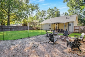 A backyard with a covered patio area, outdoor seating, and a fire pit.