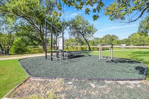 An outdoor gym area with exercise equipment, a bench, and a paved surface.