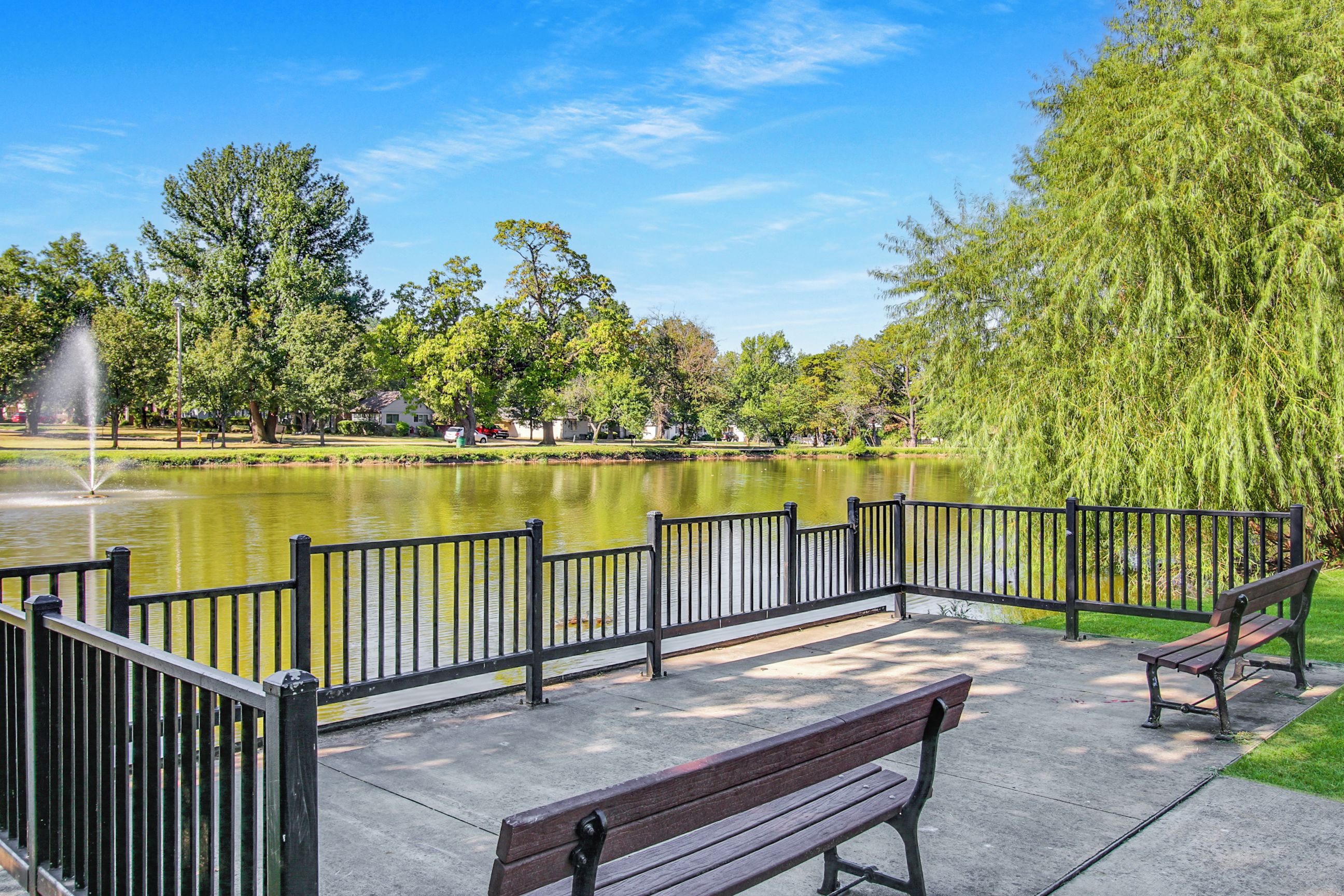 Un parc avec un étang, des bancs et une fontaine.