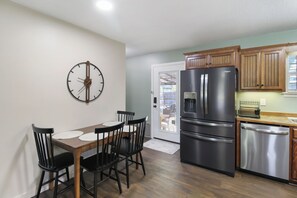 A kitchen with a dining table, chairs, a refrigerator, and wooden cabinets.