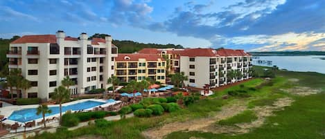 A resort with multiple buildings, a swimming pool, and a dock extending into a body of water.