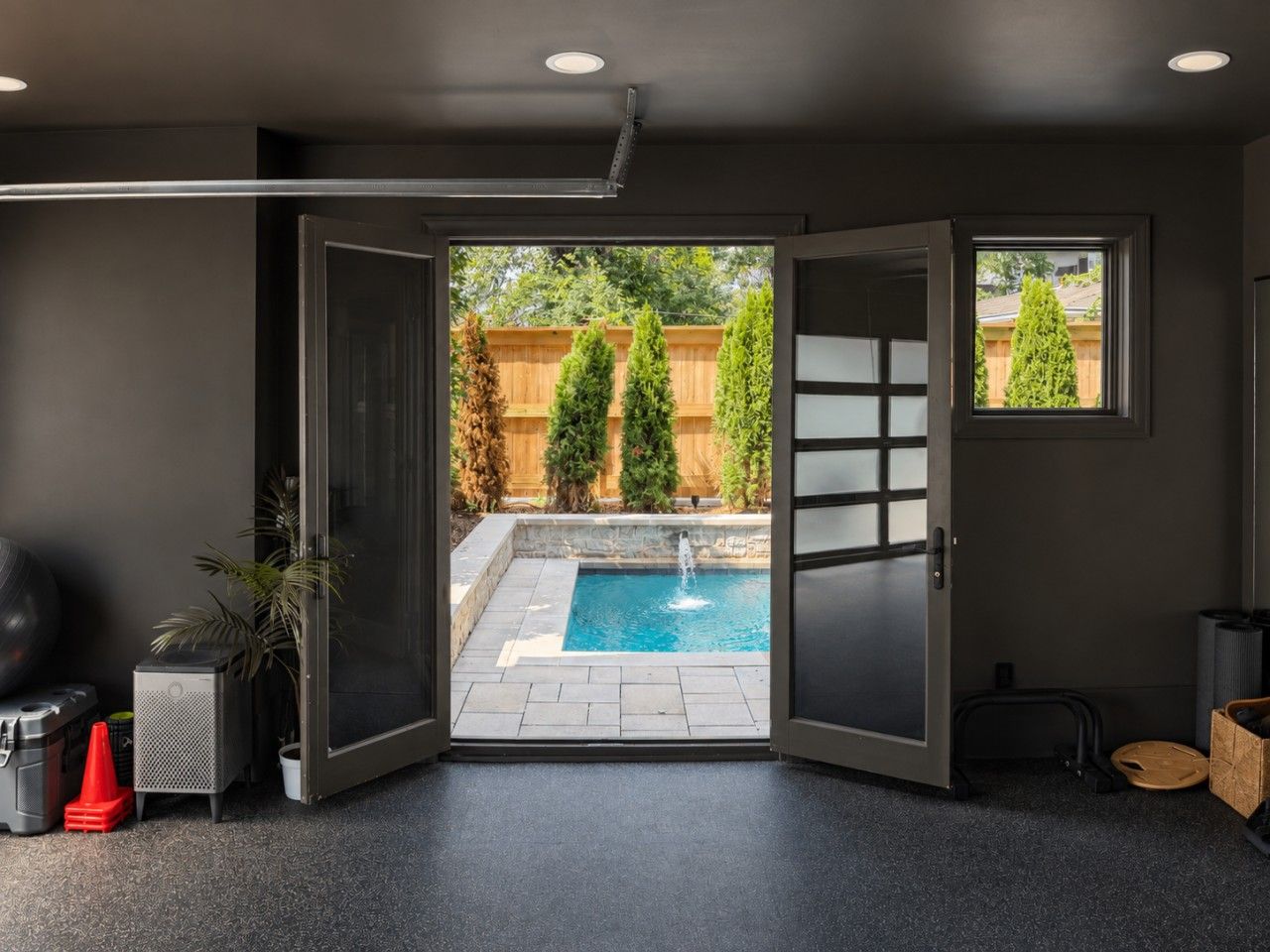 Ein Zimmer mit einer Schiebetür, die zu einem Hinterhof mit Swimmingpool, Holzfence und einer Pflanze im Topf führt.