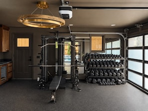A home gym with a squat rack, bench press, and a rack of dumbbells. - Maplewood Cottage • Heated Pool, Hot Tub, Gym, Grill, Fire Pit (Nashville)
