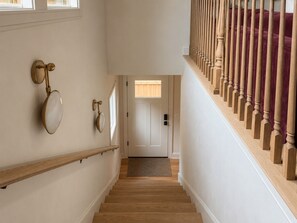 A staircase with wooden steps and a wooden handrail, leading to a door with a window above it. - Maplewood Cottage • Heated Pool, Hot Tub, Gym, Grill, Fire Pit (Nashville)