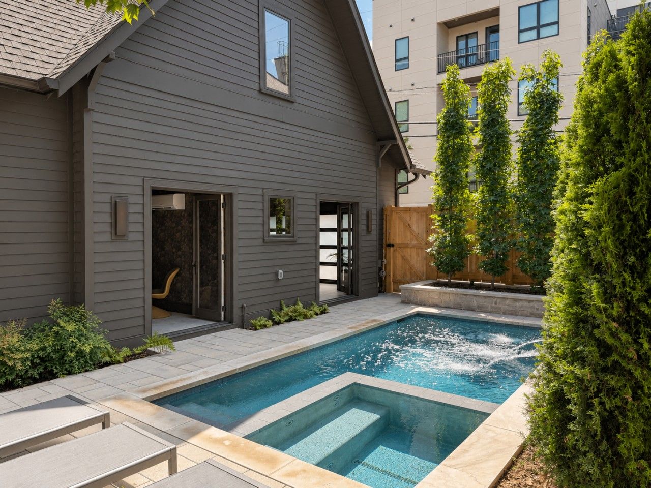 A residential property with a swimming pool, a covered patio, and a wooden fence.