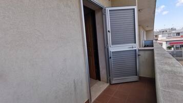 Varanda com porta de metal fechada e chão de azulejos.
