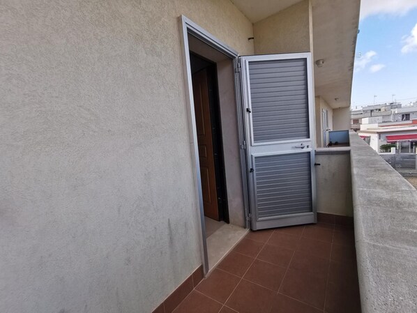 A balcony with a closed metal door and a tiled floor.