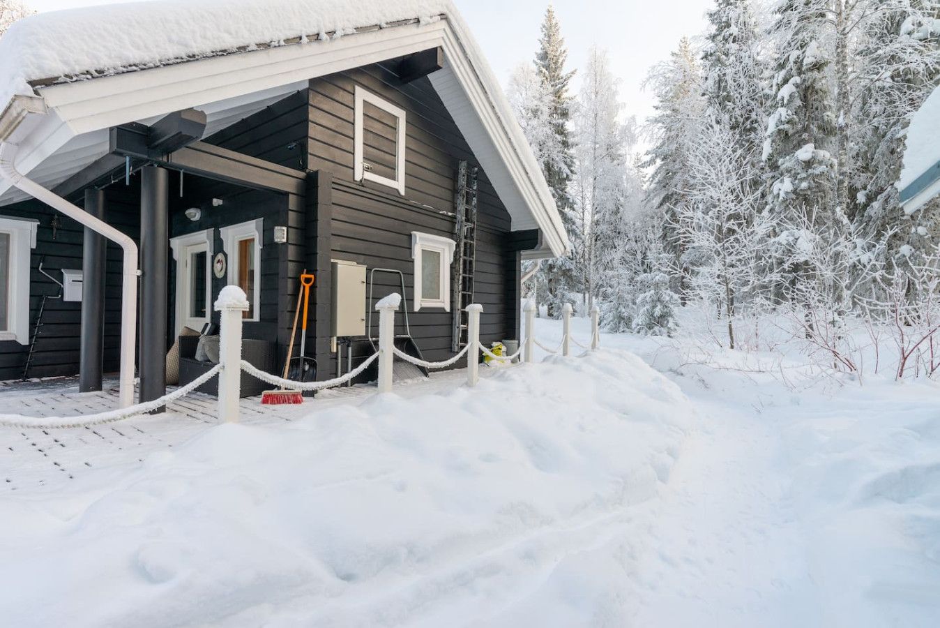 A wooden cabin with a covered entrance, surrounded by snow-covered trees.