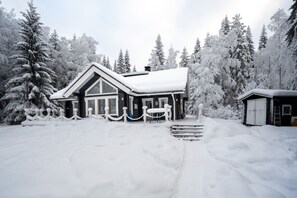 Et snedækket lodge med en stor veranda, omgivet af sneklædte træer.