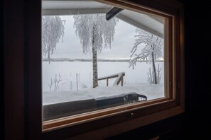 A window with a view of a snowy landscape, including a bench and trees.