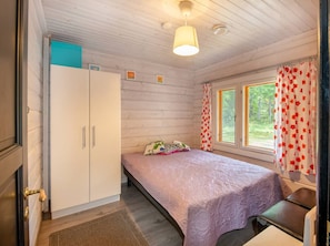 Et soveværelse med seng, skab, et vindue med gardiner og en loftslampe.