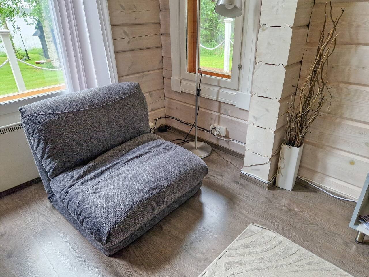 Un canapé gris dans une pièce aux murs en bois et dotée d’une fenêtre.