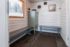 A cabin interior with a bench, a small table, a cabinet, and a window with a snowy view.