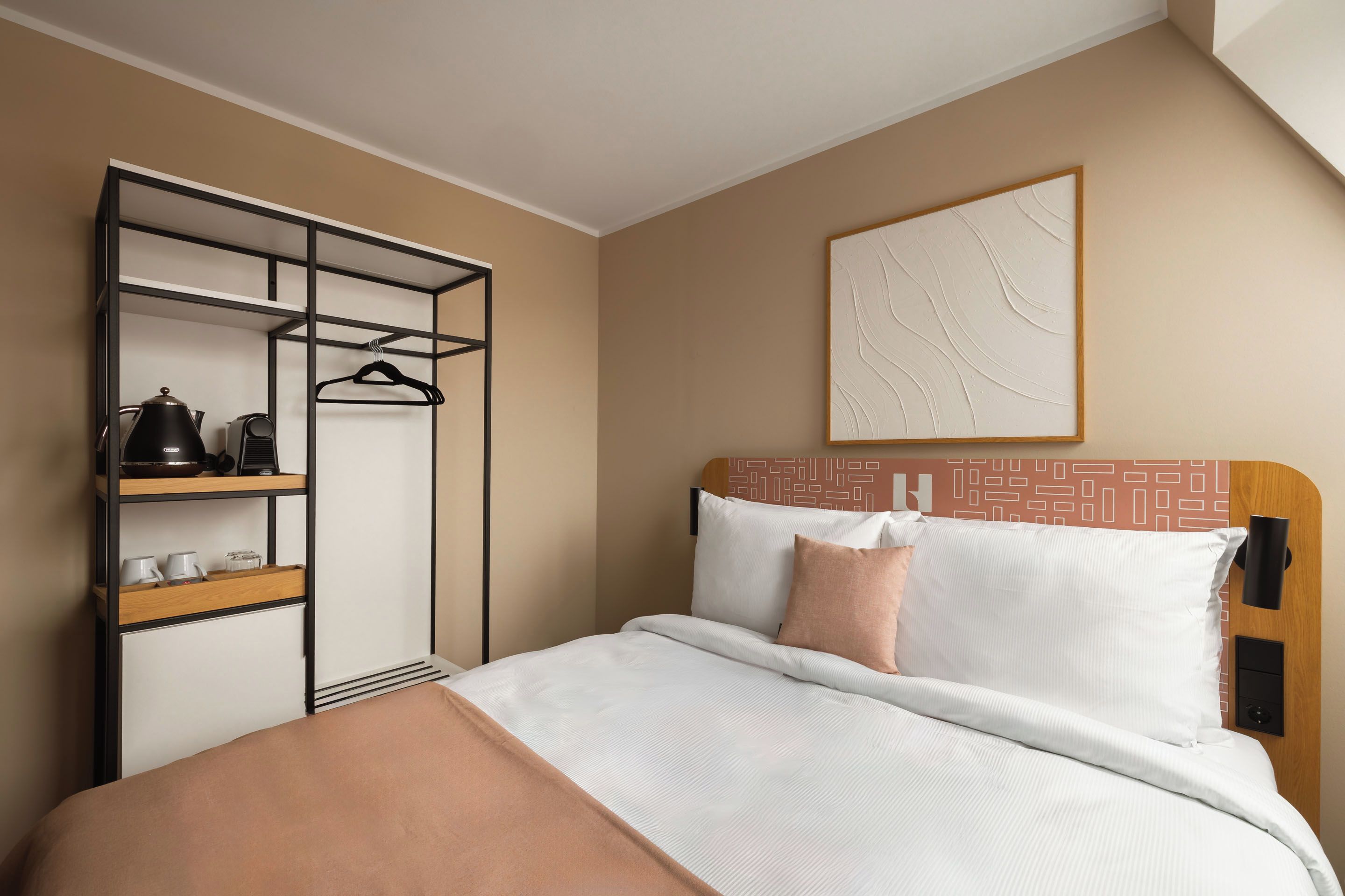 Una habitación de hotel con cama, armario y una obra de arte colgada en la pared.