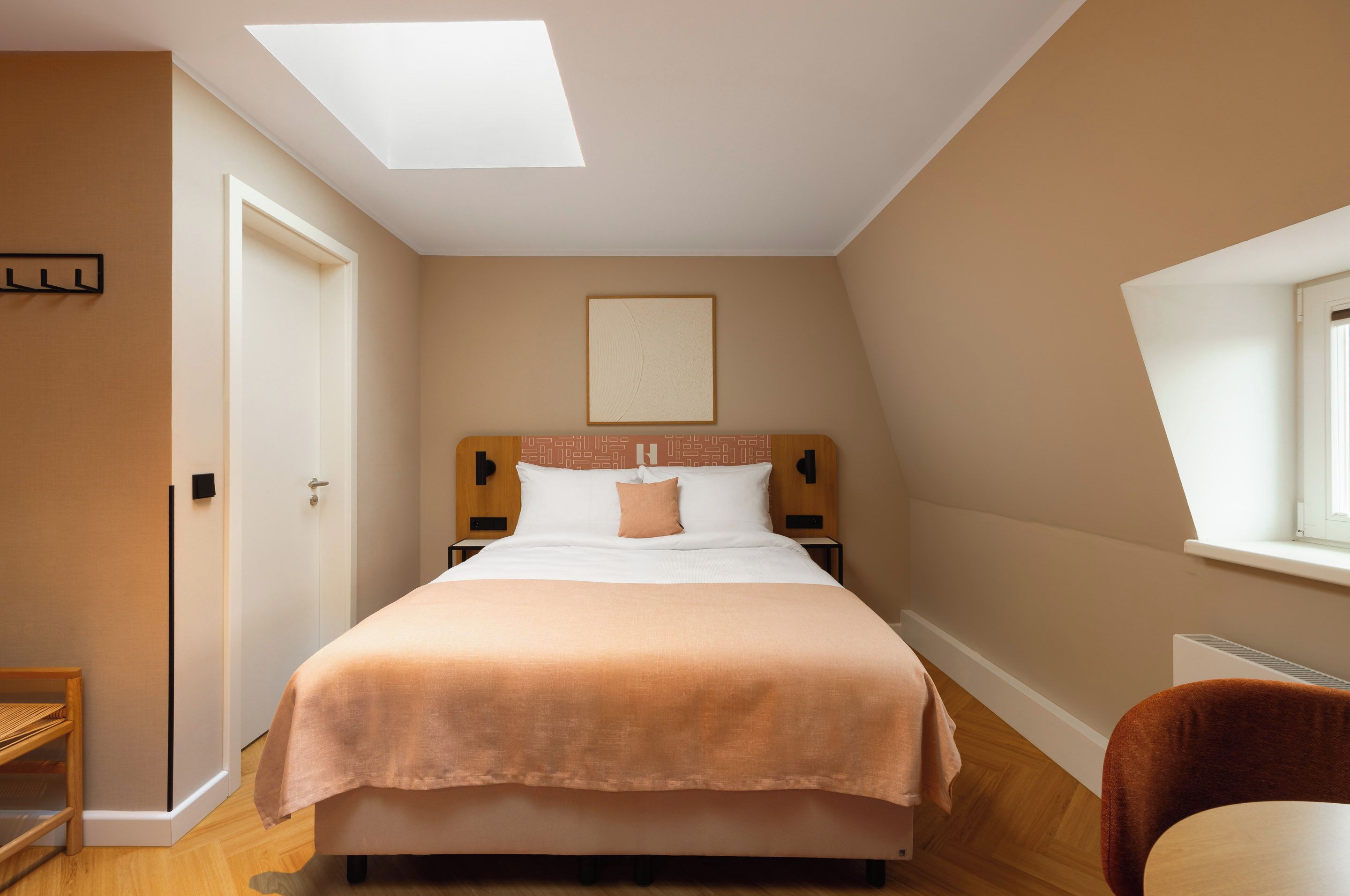Un dormitorio con una cama, una mesita de noche, una silla y un ventanal.