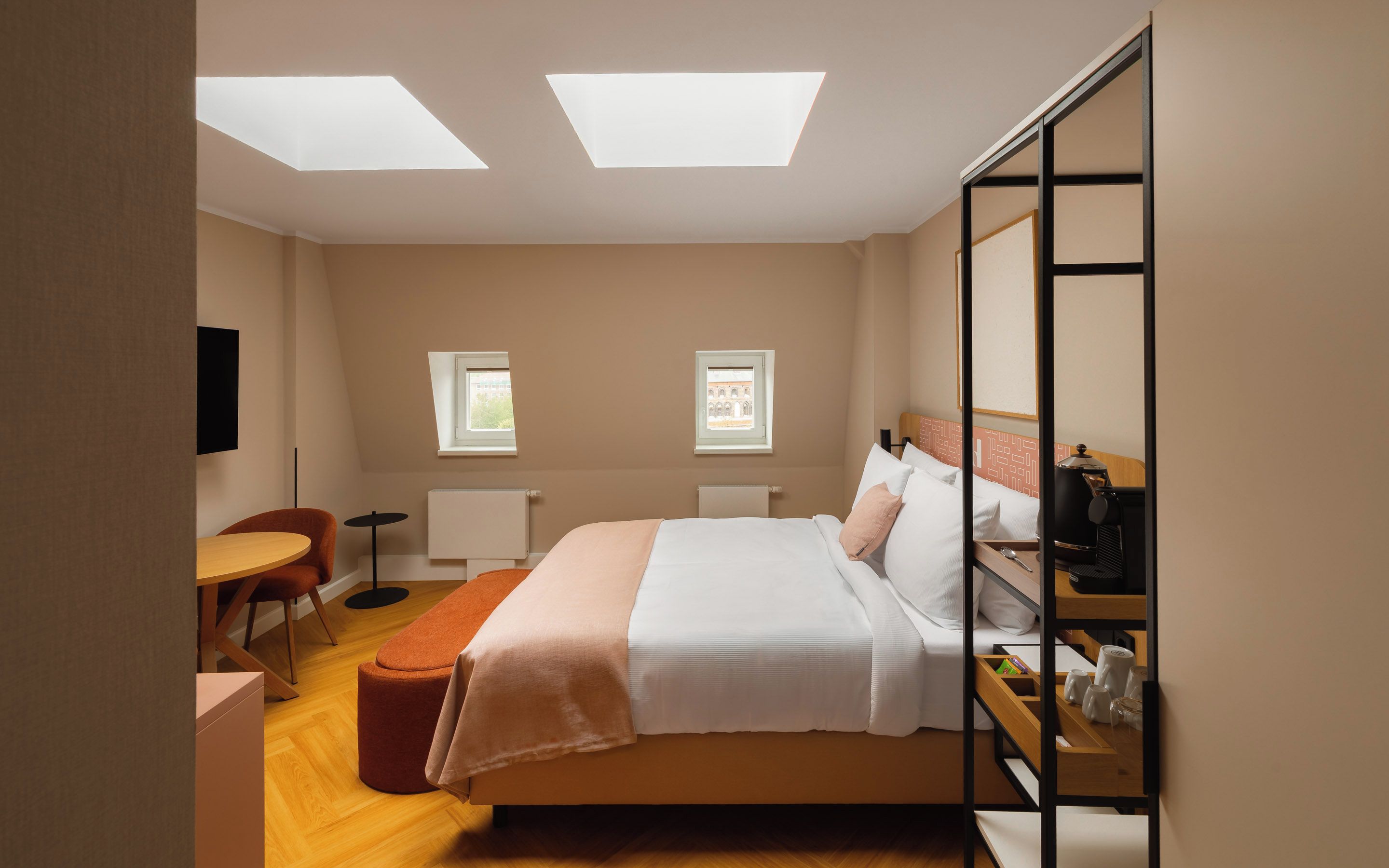 Une chambre à coucher avec un lit, une table de chevet et un bureau avec une chaise. Il y a deux fenêtres et un radiateur.