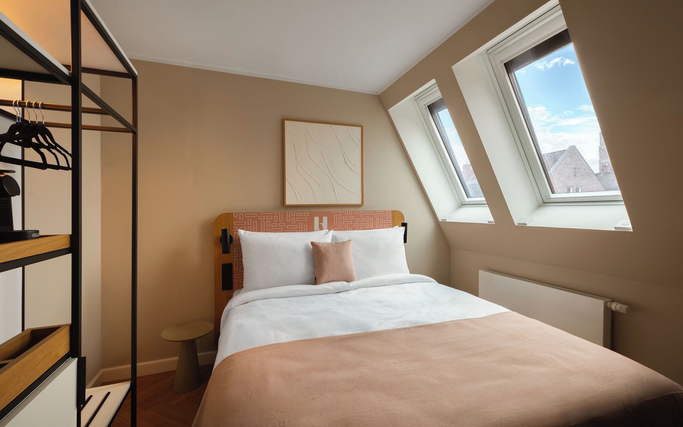 A bedroom with a bed, a bedside table, a wardrobe, and a skylight.