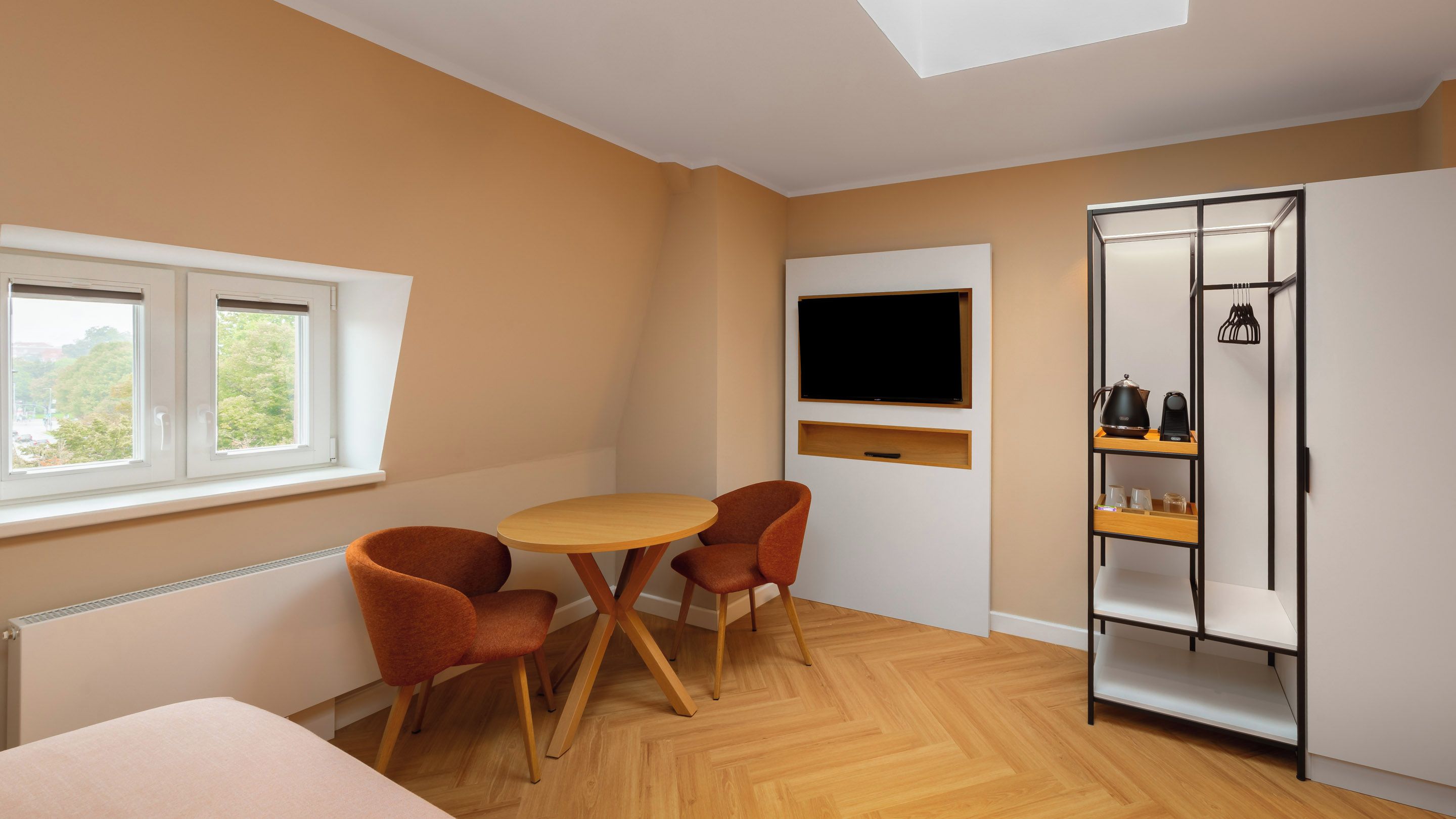 A room with a bed, a round table, two chairs, a TV, and a wardrobe.