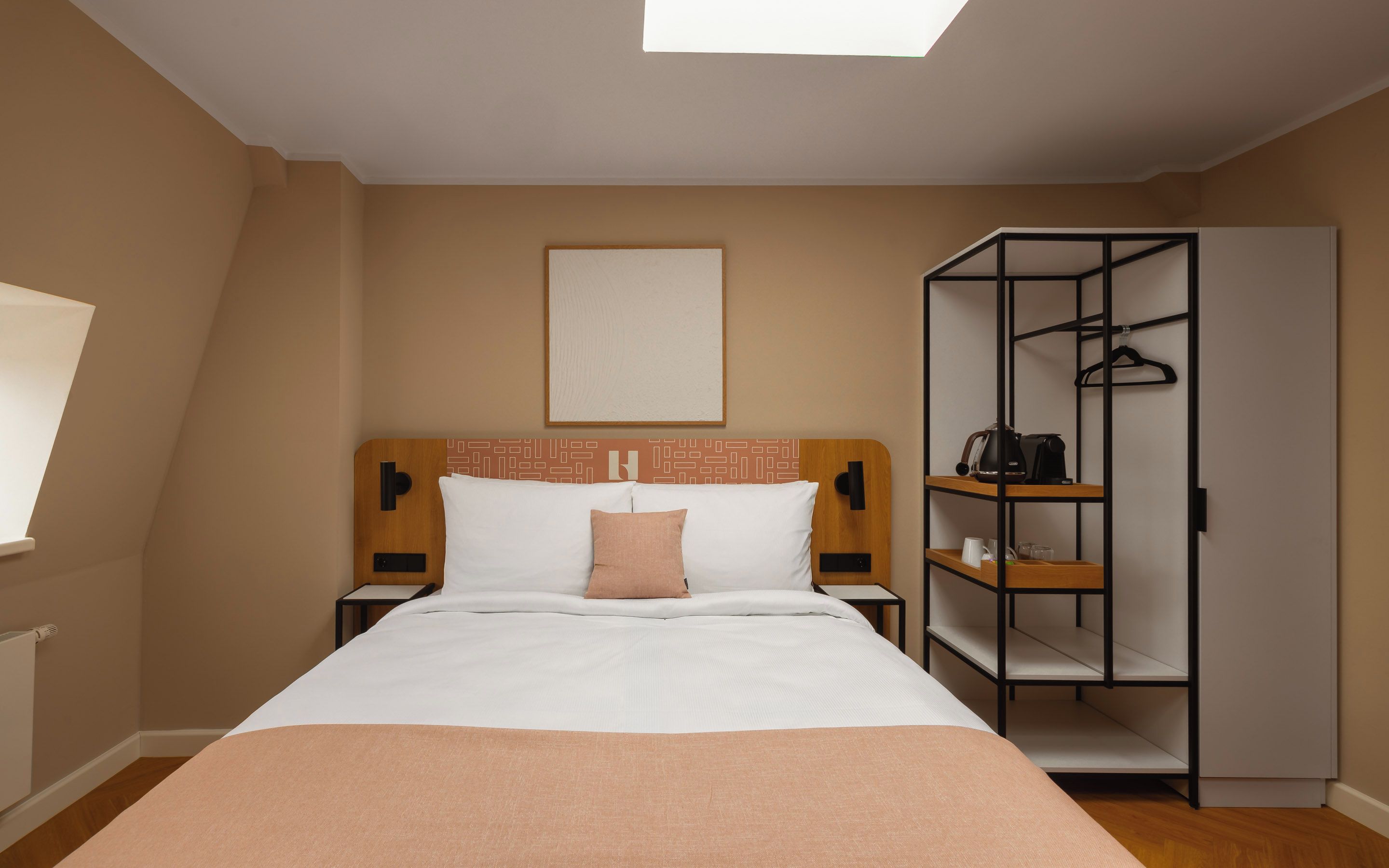 Een hotelkamer met een bed, een kledingkast, een plank en een raam.